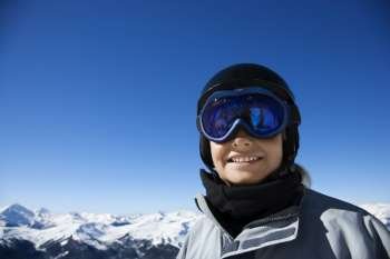 Caucasian teenage boy snowboarder wearing helmet and goggles on mountain looking at viewer.