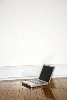 Still life of laptop on hardwood floor.