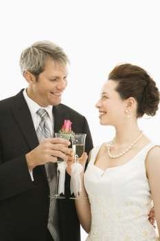 Caucasian groom and Asian bride toasting with champagne glasses.