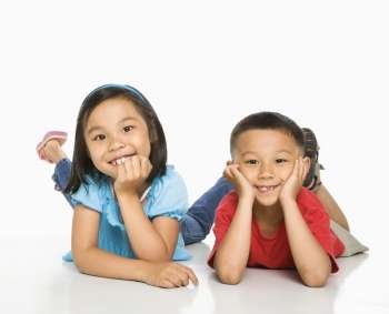 Young Asian brother and sister lying on floor with head on hands.