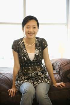 Portrait of Asian female sitting on bed.
