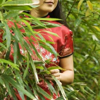 Portrait of Asian American woman in ethnic attire in bamboo forest in Maui, Hawaii.