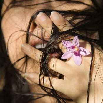 MId-adult Asian female holding flower up to her face.