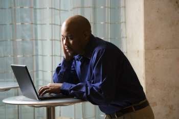 MId-adult African American male typing on laptop computer.