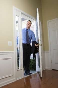 Caucasian businessman  at open door with briefcase.