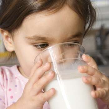 Caucasian girl drinking glass of milk.