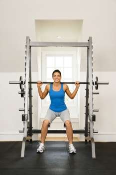 Woman lifting weights in gym smiling.