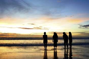 Silhouette shots of four girls on the beach enjoying the dramatic sunset
