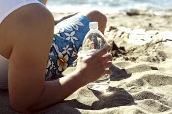 A man on the beach holding a bottle of water