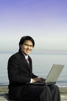 Businessman working on his laptop at the beach