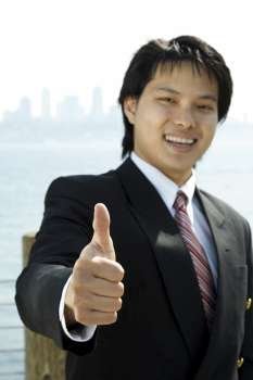 A businessman smiling with his thumbs up (focus on the thumb)