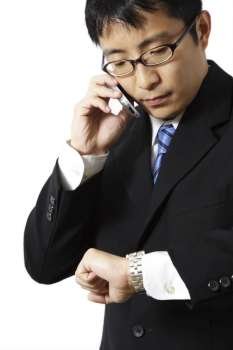 Businessman talking on the phone while looking at his watch