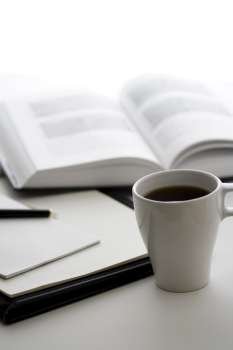 A cup of coffee, a book and a notepad