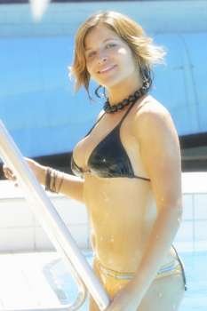 A sexy woman wearing a black bikini relaxes at the local pool.
