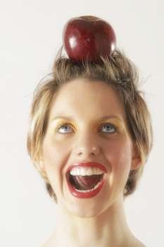 A young female model holds apple on her head like a target. .
