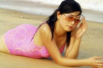 A sexy young Chinese model wears pink and poses by the sea.