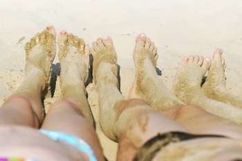 Row of children´s feet on a beach covered in sand