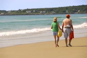 Mature couple walking on a sandy beach holding hands