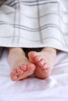 Child´s feet sticking out of a blanket in a bed