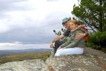 A parent and a child sitting on a cliff edge enjoying scenic view