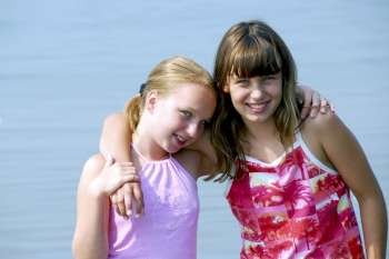 Portrait of two preteen girls standing in water