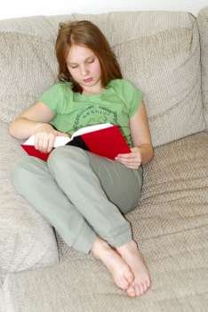 Young girl reading a book on a couch