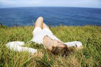 Woman lying in grass and sea background