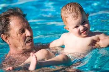 Elderly man swimming with a baby