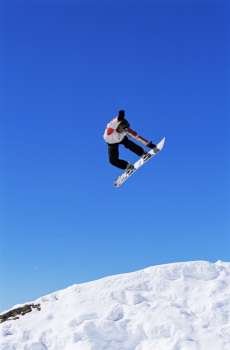 Snowboarder doing jump on hill