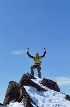 Mountain climber standing on snowy mountain victorious and smiling
