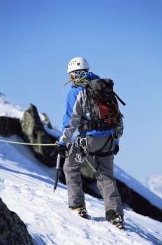 Mountain climber going up snowy mountain (selective focus)