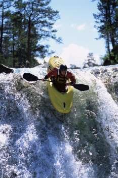 Kayaker in rapids going over waterfall (selective focus)