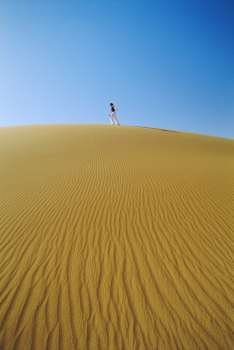 Woman outdoors walking in the desert (far away)
