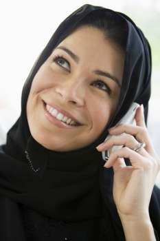 Woman indoors on cellular phone smiling (high key)