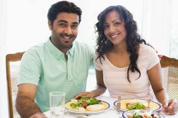 Couple sitting at dinner table smiling (high key)