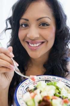 Woman holding bowl of salad and smiling (high key/selective focus)