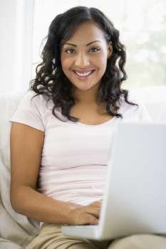 Woman in living room with laptop smiling (high key/selective focus)