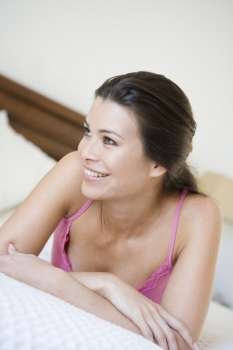 Woman relaxing on bed in bedroom smiling (selective focus)