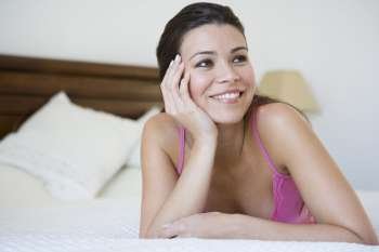 Woman relaxing on bed in bedroom smiling (selective focus)