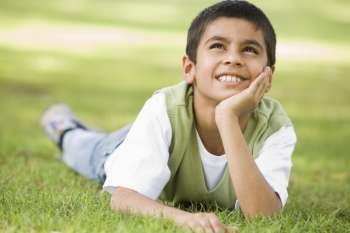 Young boy outdoors lying in grass and smiling (selective focus)