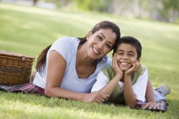 Mother and son outdoors in park with picnic smiling (selective focus)