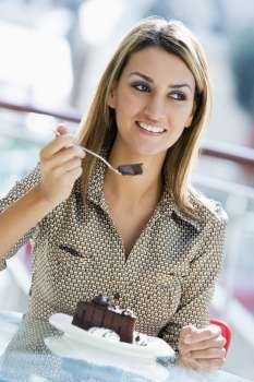 Woman at restaurant eating dessert and smiling (selective focus)