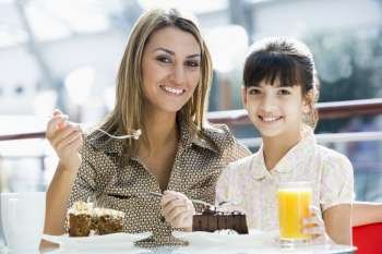 Mother at restaurant with daughter girl eating dessert and smiling (selective focus)