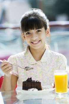 Young girl at restaurant eating dessert and smiling (selective focus)