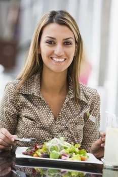 Woman at restaurant eating salad and smiling (selective focus)