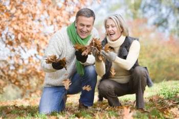 Couple outdoors looking at leaves and smiling (selective focus)