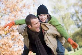 Father outdoors piggybacking son and smiling (selective focus)