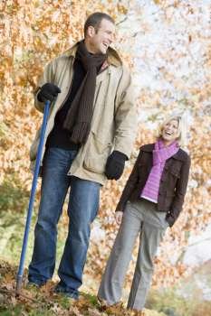 Couple outdoors raking leaves and smiling (selective focus)
