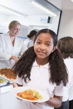 Students in cafeteria line with one holding her healthy meal looking at camera
