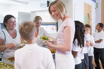 Students in cafeteria line with teacher at lunchtime